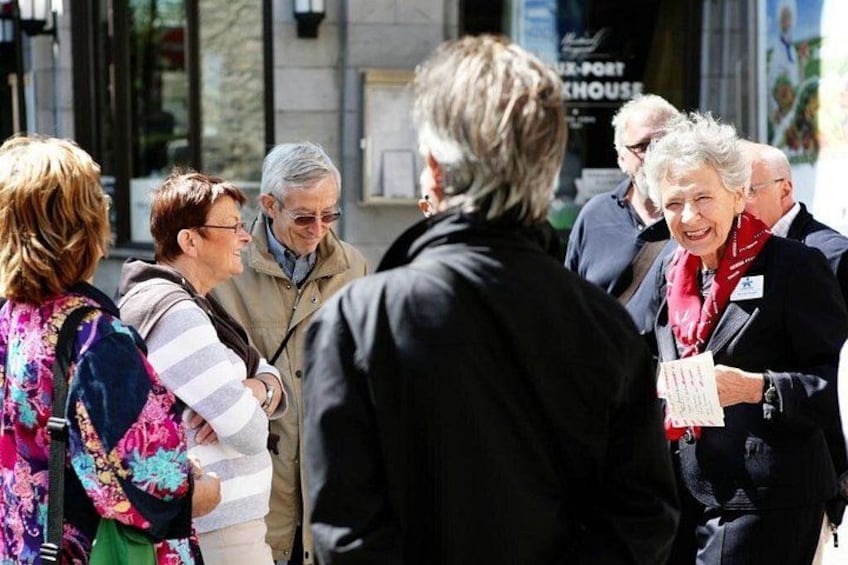 A group of people standing outdoors, possibly in a public space with a building in the background. 3