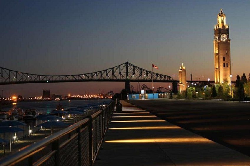 A bridge over a body of water, a clock tower, and a lit-up bridge at dusk. 2