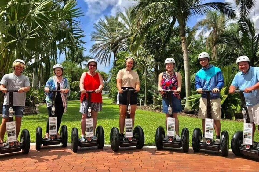 A group of people on segways in a tropical setting with palm trees. 1