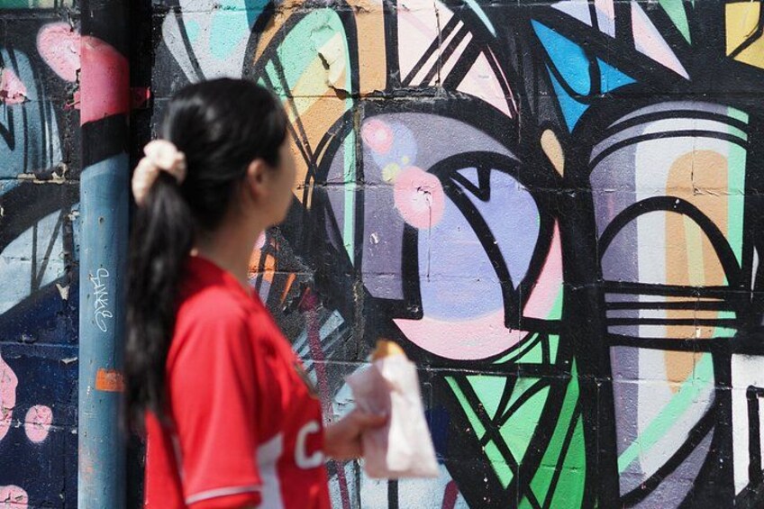 A person in a red shirt painting graffiti on a wall. 2