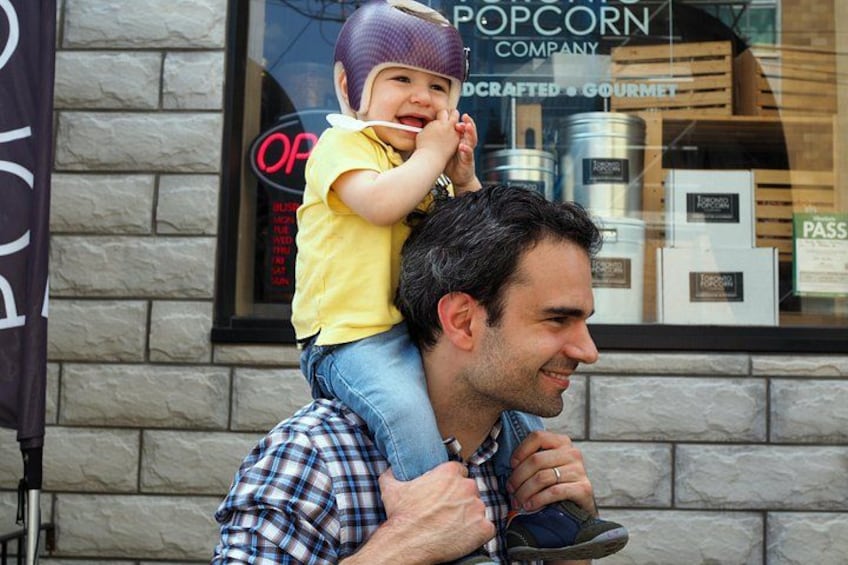 Un hombre lleva a un niño sobre sus hombros frente a un edificio con un letrero que dice 'POP CORN COMPANY'. 4
