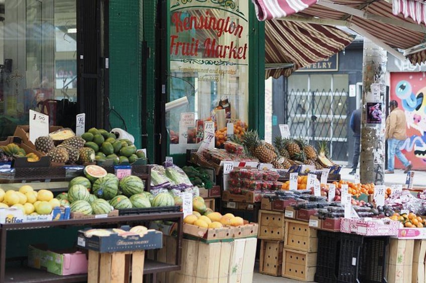 Un mercado de frutas con diversas frutas expuestas, entre ellas sandías, piñas y naranjas. 3