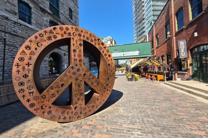 A large peace symbol with various religious symbols on a cobblestone street. 5