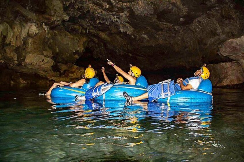 People in blue inflatable rafts in a cave with water. 1