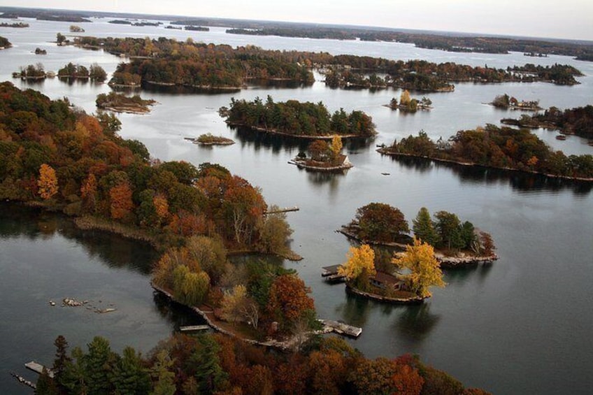 A network of islands surrounded by calm water, dense forests with autumn foliage, and a clear sky. 4