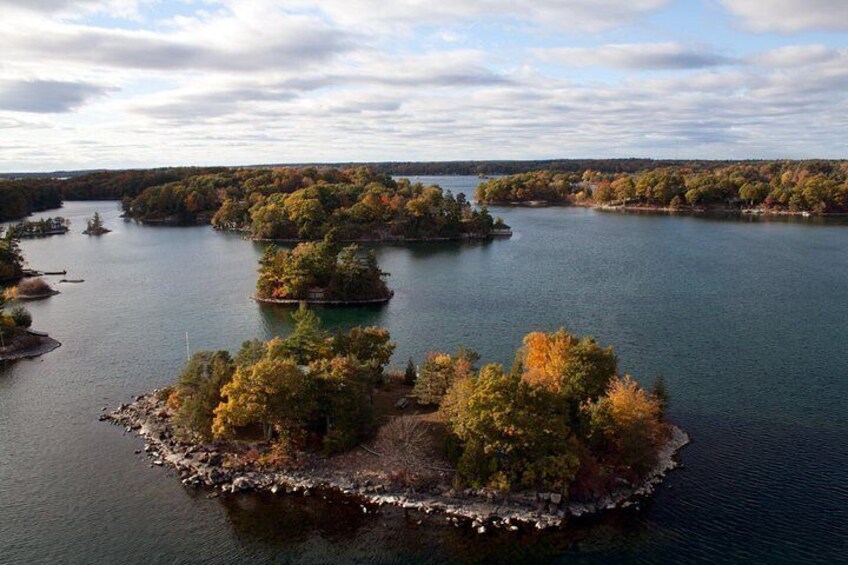 A lake with several small islands, surrounded by trees with autumn foliage. 2