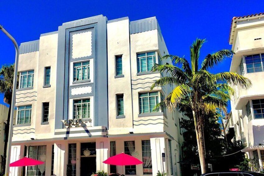 A building with a modern design, featuring a central entrance with a decorative archway and two red umbrellas. 3