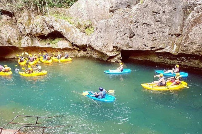 Des personnes pratiquent le kayak dans une rivière, avec des falaises rocheuses en arrière-plan. 3