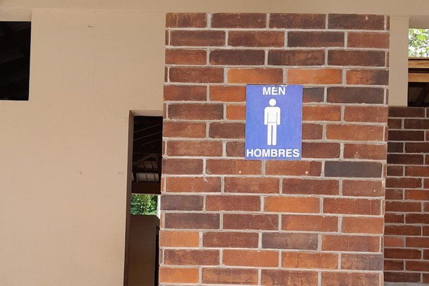 Un panneau bleu avec le symbole masculin et le mot « HOMMES » sur un mur de briques. 2