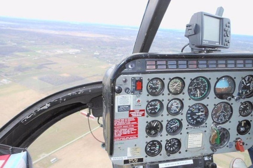 Cabina de helicóptero con varios indicadores y vista del paisaje circundante. 5