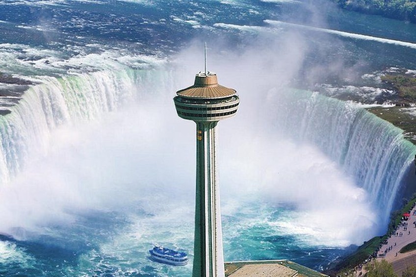 A tower with a spiral staircase, a large waterfall, and a boat in the water. 3