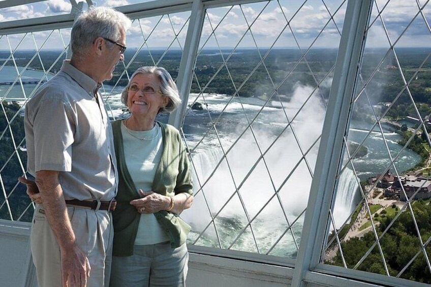A couple standing by a large window overlooking a waterfall. 2