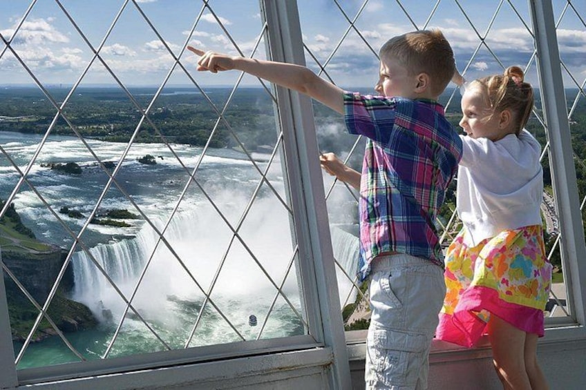 Two children observing a waterfall through a glass barrier. 2
