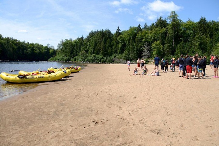 Ein Sandstrand mit gelben Kajaks und Menschen, die sich ans Wasser begeben haben. 2