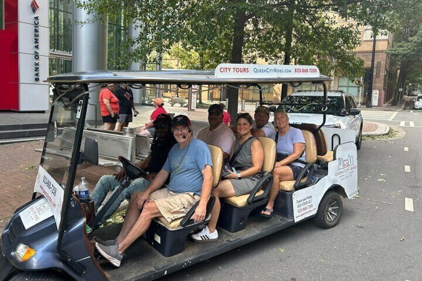 Een golfkarretje met vijf passagiers tijdens een stadsrondrit. 1