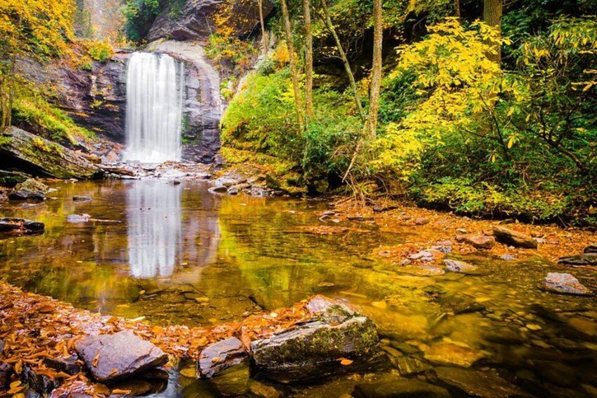 A waterfall, clear water, rocks, and autumn foliage. 3