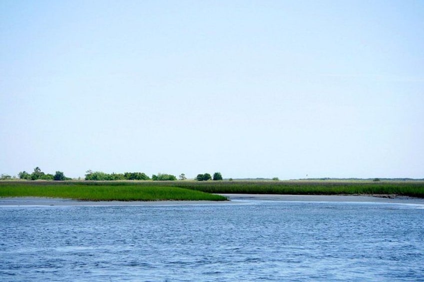 A calm river with grassy banks and a clear sky. 3