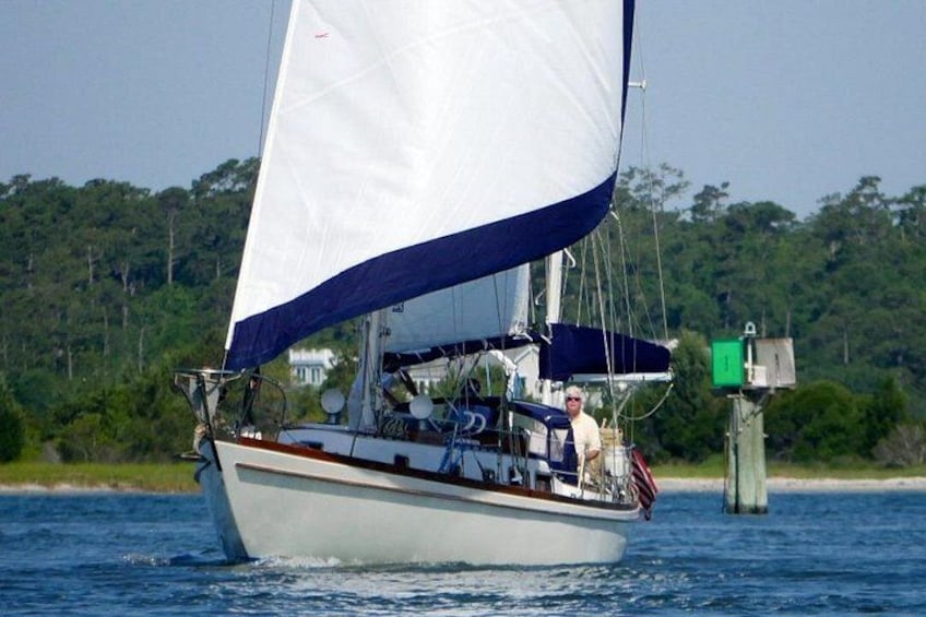 A sailboat with a white hull and blue sails on a body of water. 5