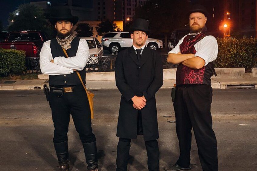 Tres hombres de pie en una calle por la noche. 3