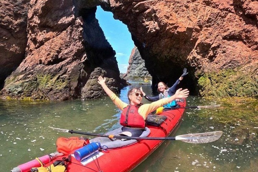 Un kayak rojo con una persona que lleva chaleco salvavidas, un remo y una bolsa. 3