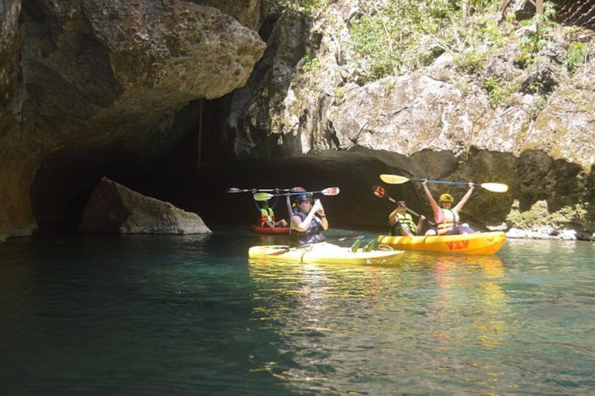 Kayakers in a cave opening with clear water. 1
