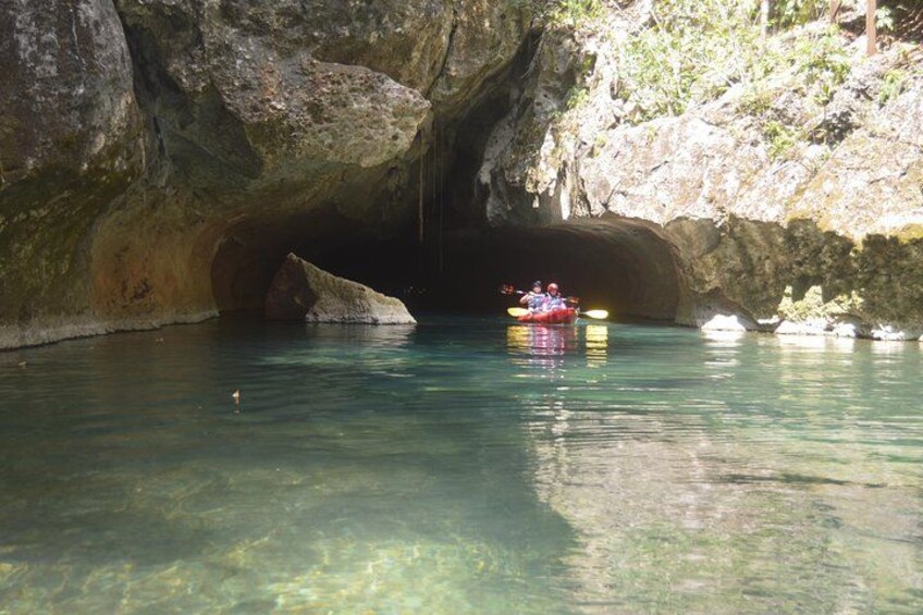 A kayaker in a cave with clear water and rocky walls. 2