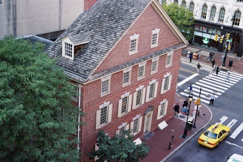 A red brick building with a sloped roof, a crosswalk, and a yellow taxi on the street. 3