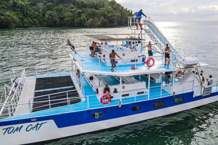 Un bateau appelé TOM CAT, avec des personnes à bord, entouré d’eau et de verdure. 1