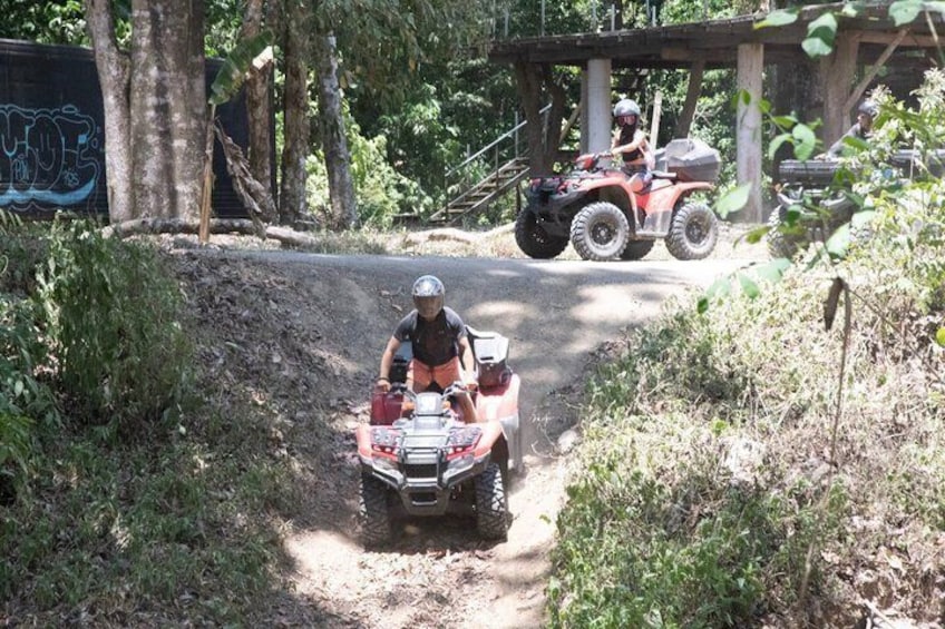 Una persona manejando un cuatrimoto por un sendero de tierra en una zona boscosa. 3