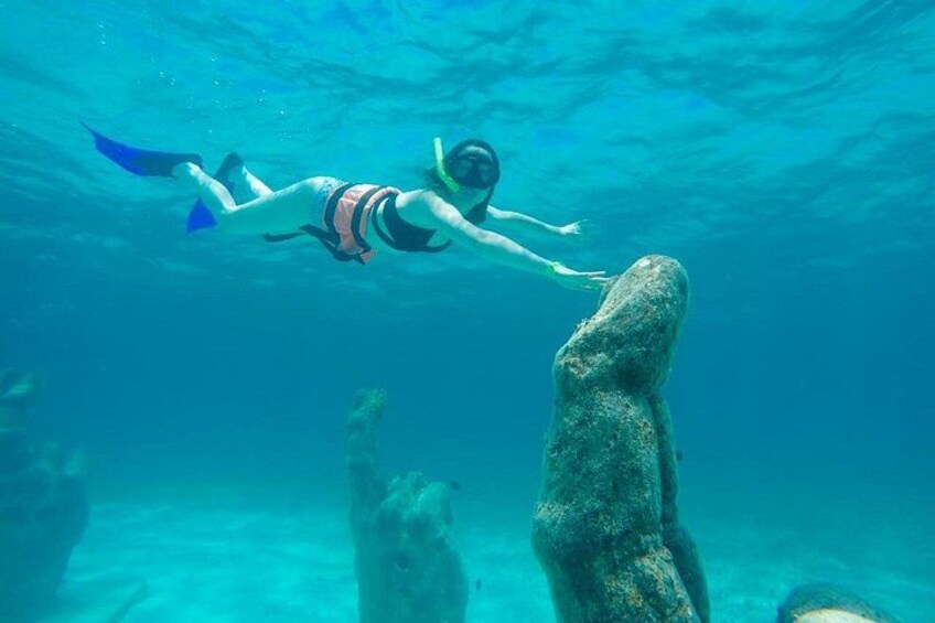 A person snorkeling underwater near a large rock formation. 2