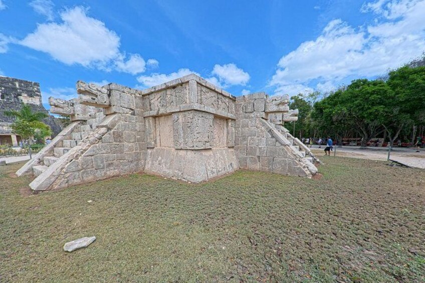 A stone pyramid structure with staircases on a grassy area. 2
