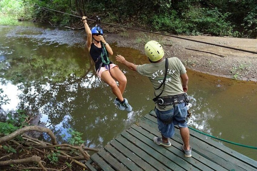 A person zip-lining over a river, another person assisting on a dock. 3