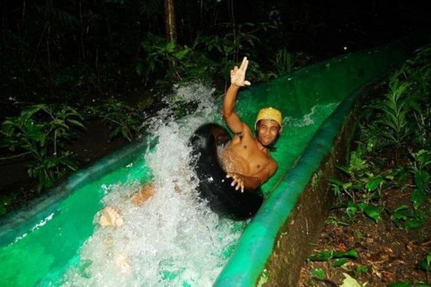 Eine Person saust auf einer Wasserrutsche durch ein bewaldetes Gebiet. 5