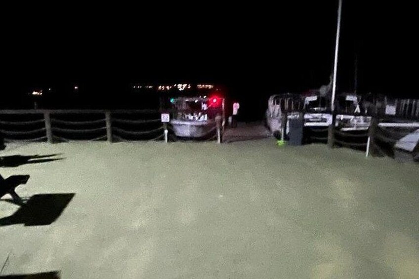 A parking area at night with vehicles and a fence. 4