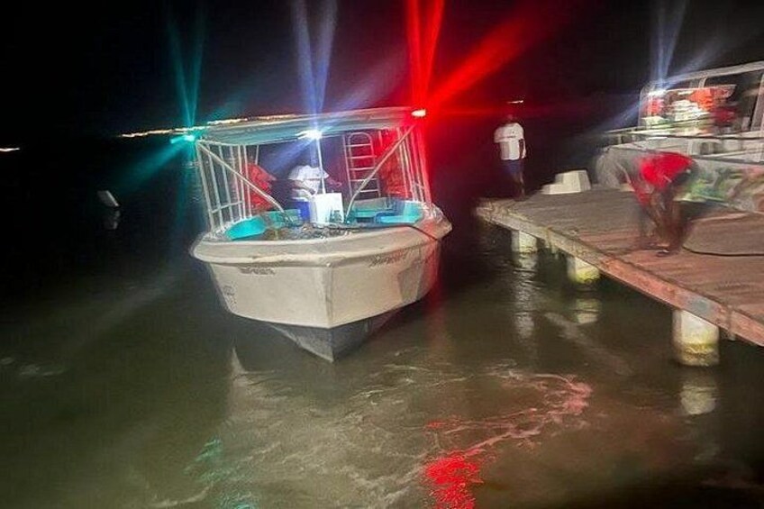 A boat docked at a pier with colorful lights. 3