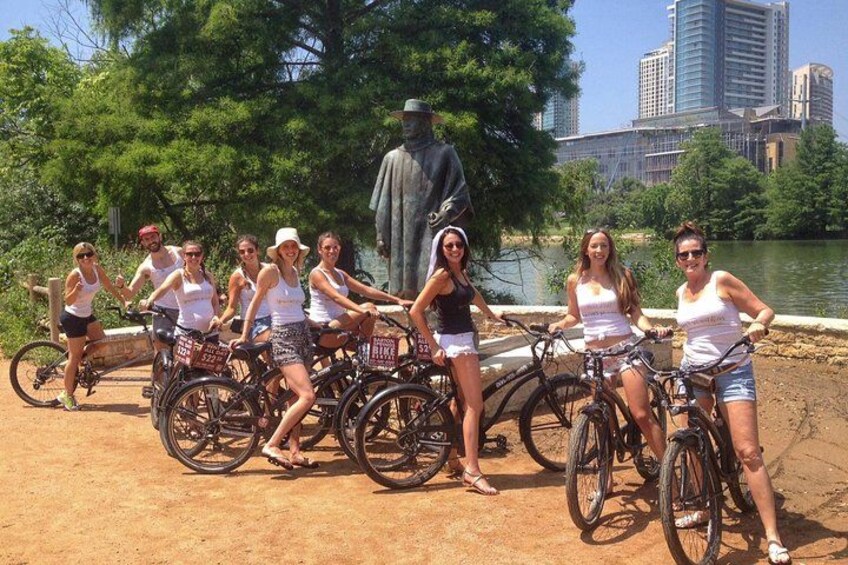 A group of people on bicycles near a body of water with a statue in the background. 2