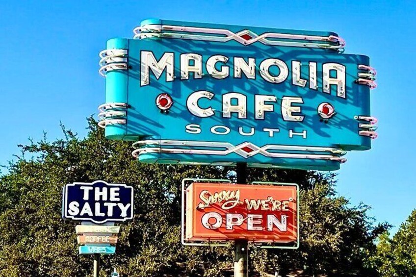 A vintage neon sign for Magnolia Cafe South with additional signs for The Salty and a 'Sunny We're Open' message. 3