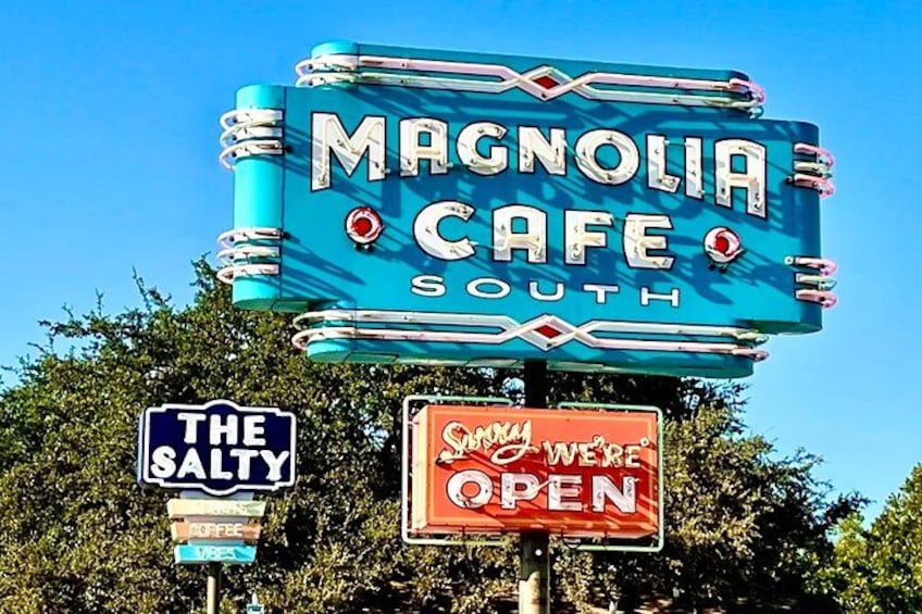 Een antiek neonbord voor Magnolia Cafe South, een bord voor The Salty, en een bord dat aangeeft dat het café geopend is. 2