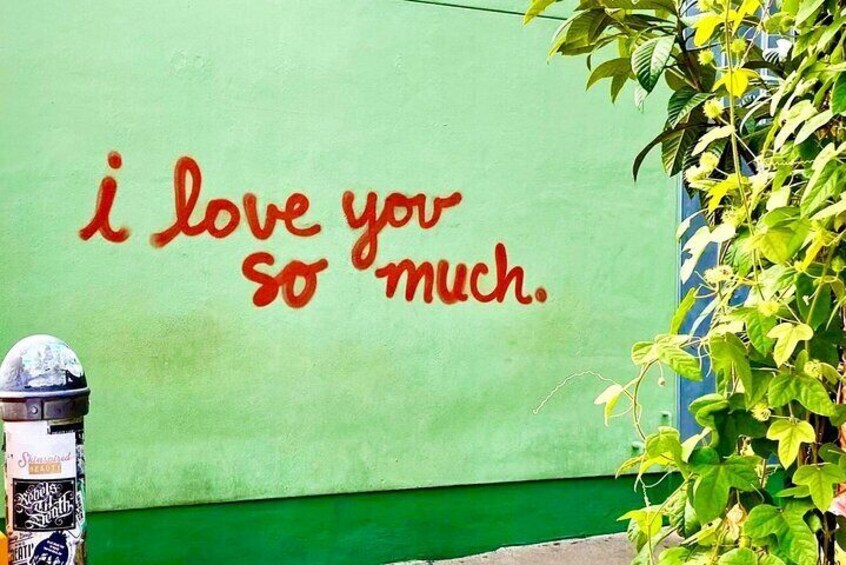 A green wall with red graffiti saying 'i love you so much.' 2