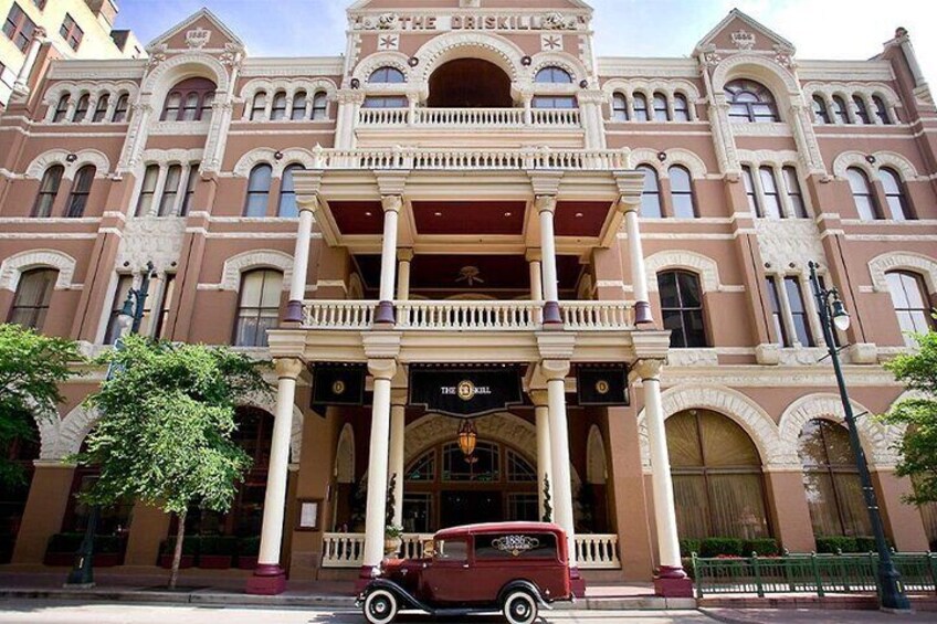 A historic building with ornate architecture, a vintage car parked in front, and a clear blue sky. 5