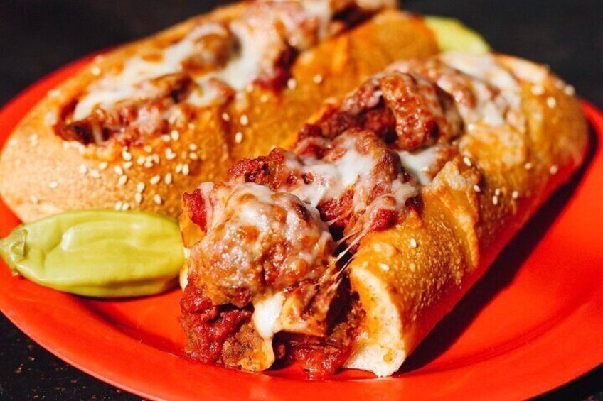 A sandwich with melted cheese and sauce, served on a red plate. 3