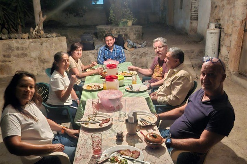 A group of people sitting around a table outdoors, eating and drinking. 5