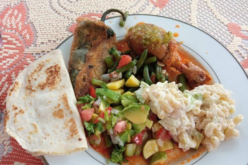 A plate of food with a tortilla, fish, vegetables, and a creamy side dish. 2