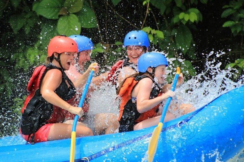 People in a blue raft with helmets, paddles, and life jackets. 5