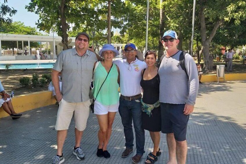 A group of people standing on a paved area with trees and a pool in the background. 5