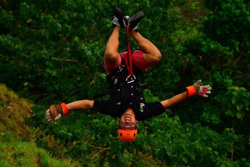 A person bungee jumping with a harness and helmet, surrounded by dense green foliage. 2