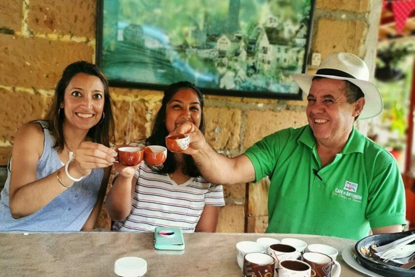 Tre persone sedute a un tavolo con tazze di caffè, una camicia verde e un cappello. 3