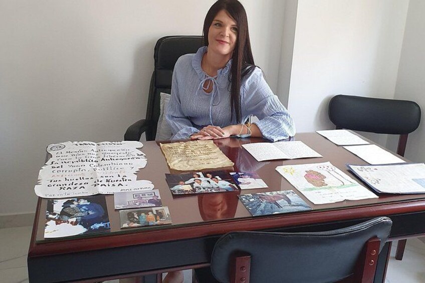 A person sitting at a desk with papers, a computer, and various documents. 3