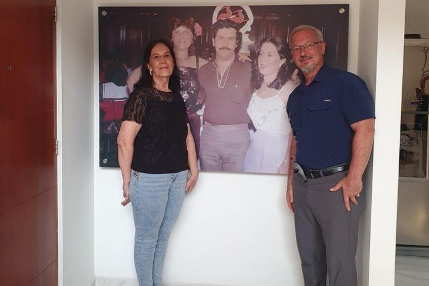 A wall with a framed photograph of a family. 2