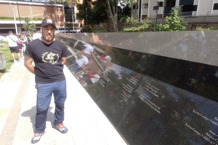 En man som står framför ett svart monument med inskriptioner, och monumentet har en reflekterande yta. 5